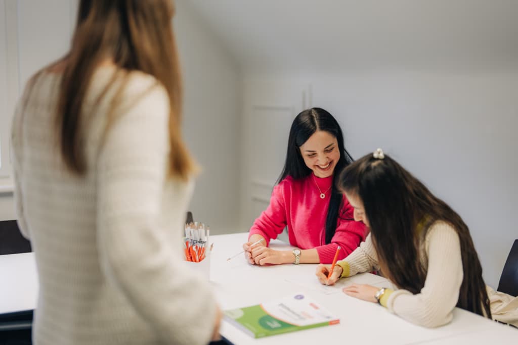 Dieses Foto zeigt zwei Teilnehmerinnen, die Deutsch lernen. Die Teilnehmerinnen trainieren zu schreiben. Unsere Deutschkurse in Luzern und Zug warten auf Sie.